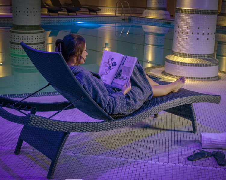 woman relaxing by pool at q hotels dunston hall in norfolk