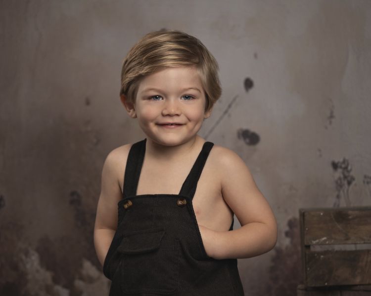 young boy wearing black dungarees on a child photoshoot