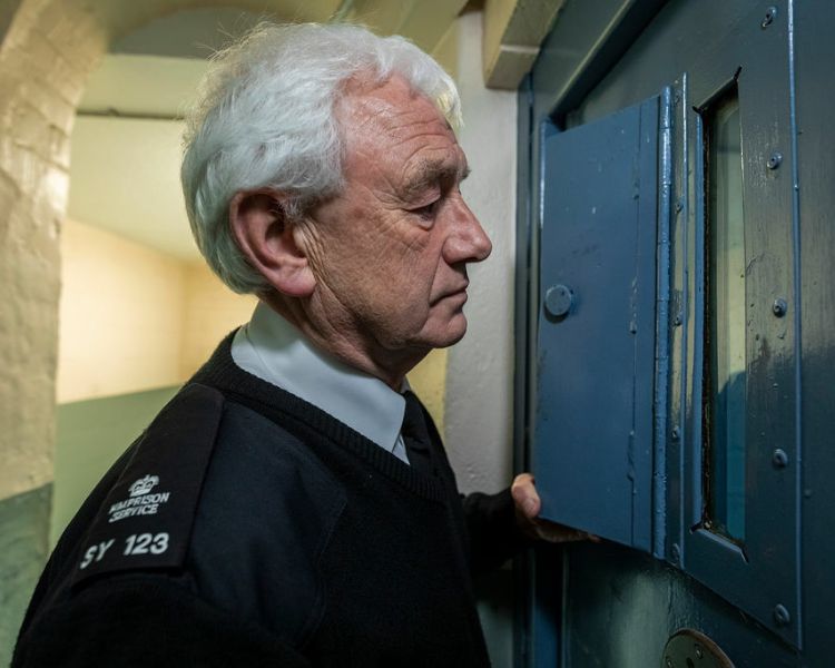 a prison guide looking through a cell door as part of a guided tour of a former prison experience day