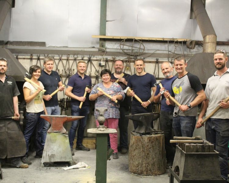 Group posing with their axes on blacksmith experience day