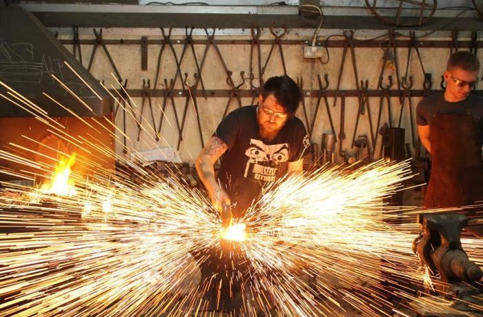 Man striking hot metal with sparks flying