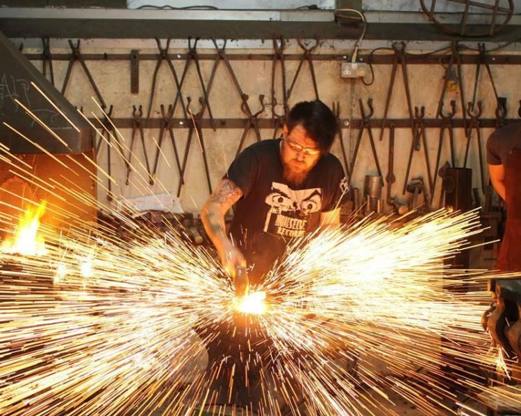 Man striking hot metal with sparks flying