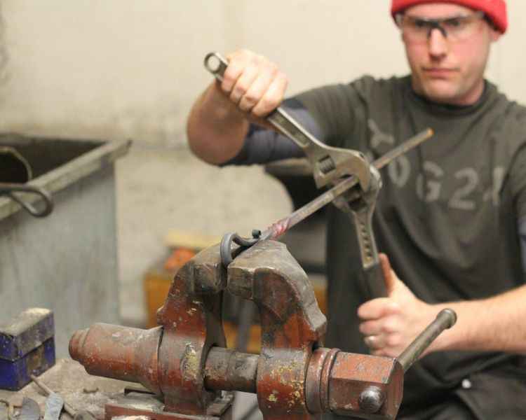 Man twisting hot metal in a vice