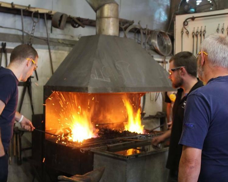 People heating up metal in forge on blacksmith experience