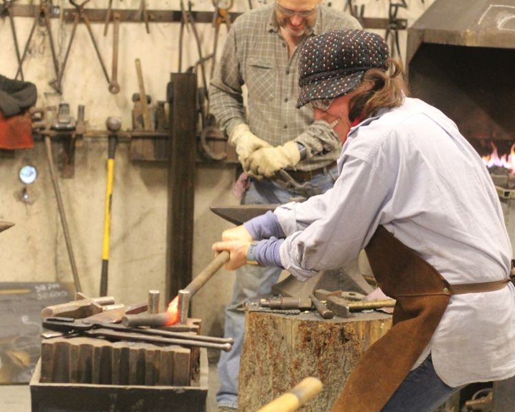 Woman bending hot metal on a blacksmith experience