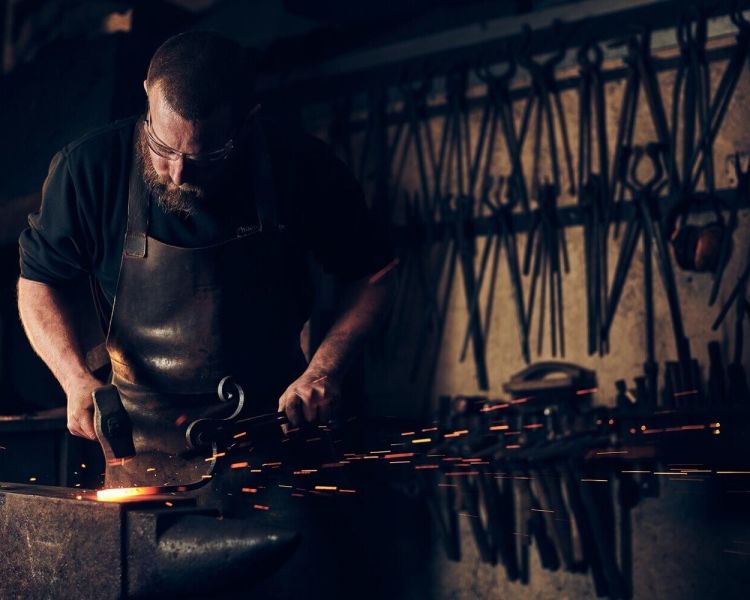 Man hammering hot metal with sparks flying