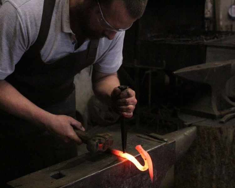 Man manipulating hot metal on a blacksmith experience day