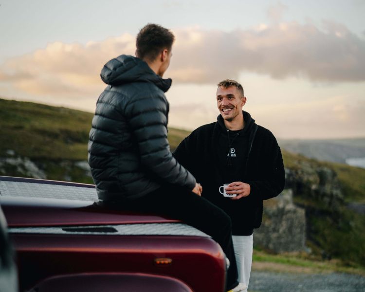 2 men chatting by land rover defender
