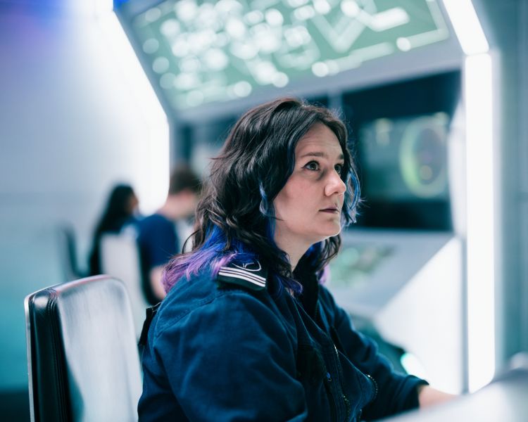 woman looking at computer screens on spaceship simulator experience in london