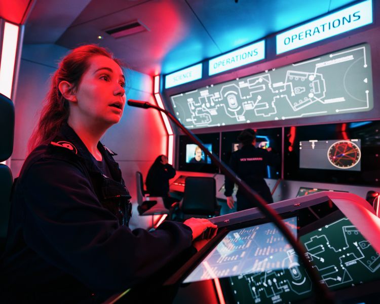 woman in the captain role talking into microphone on immersive spaceship simulator experience in london