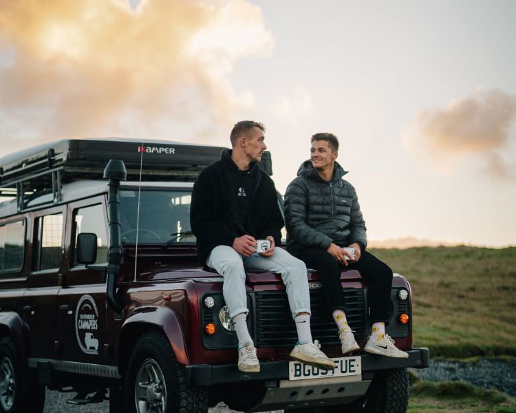 Men sitting on bonnet of land rover defender