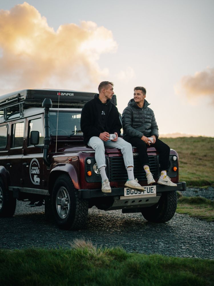 Men sitting on bonnet of land rover defender