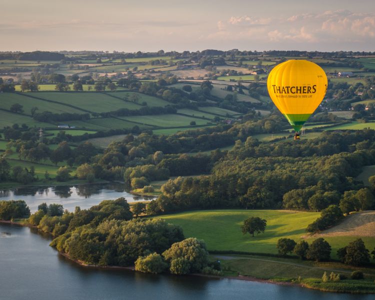 Hot air balloon flying over kent countryside and lake