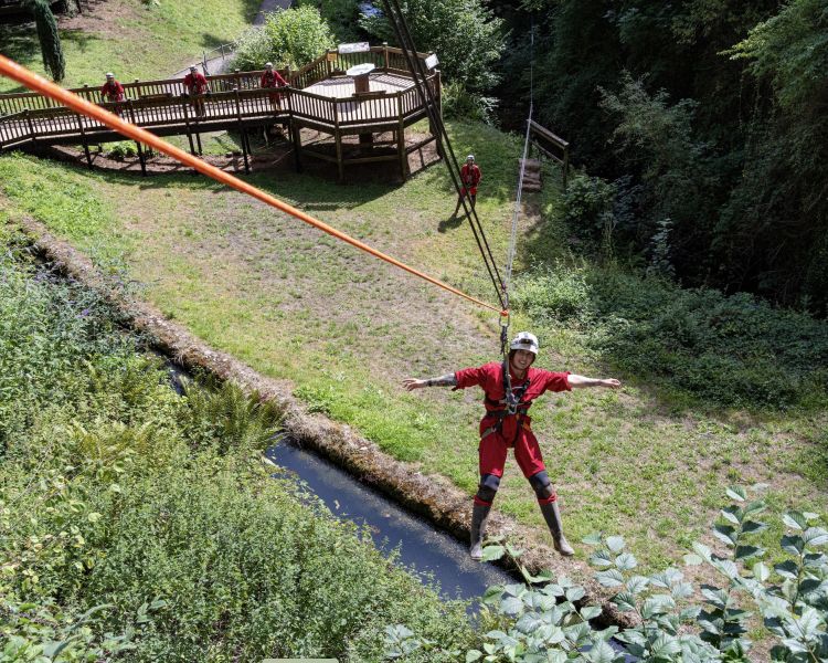 woman zip lining out of cave down to the ground