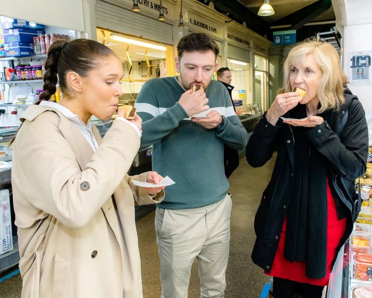 Tour group sampling food in market on welsh food tour