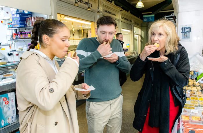 Tour group sampling food in market on welsh food tour