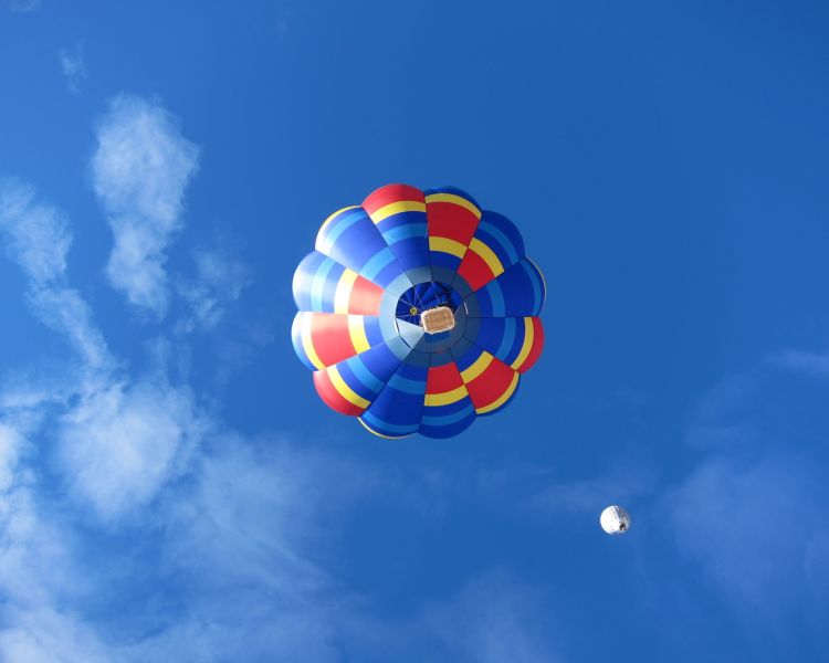view of colourful hot air balloon from below against a blue cloudy sky