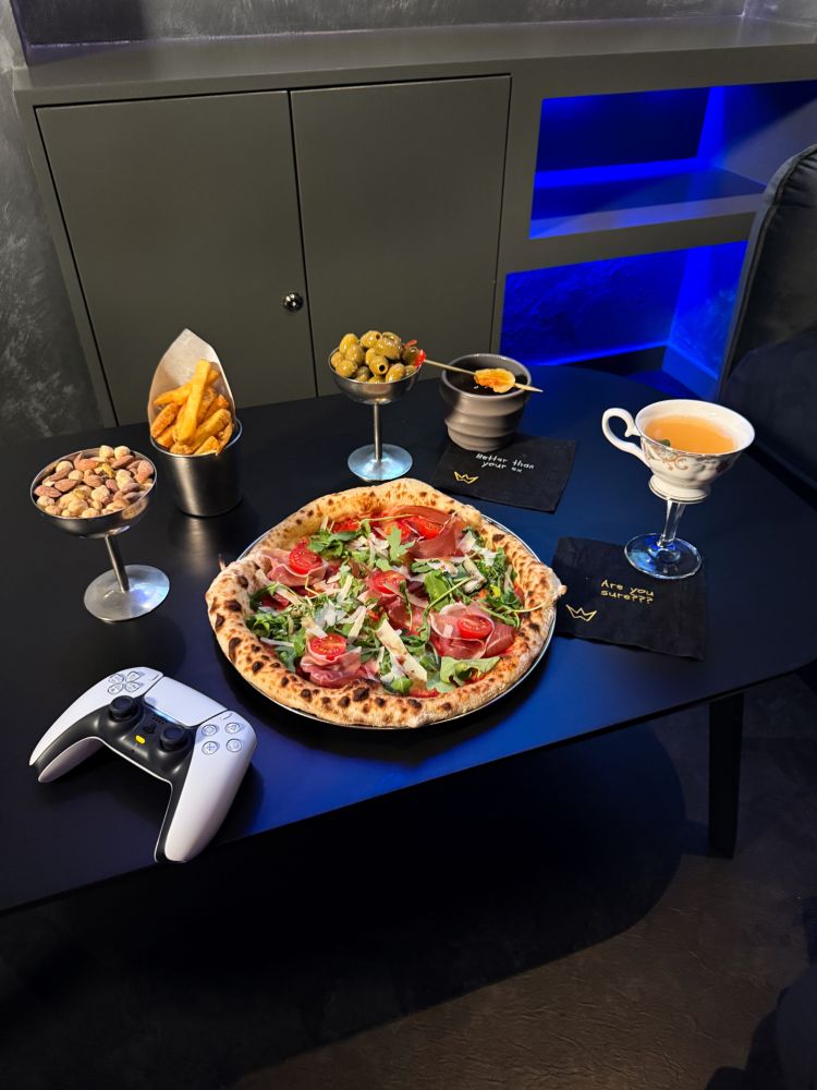 pizza, nibbles and cocktails on table at gaming bar in london