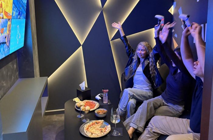 three people playing playstation at gaming bar in london