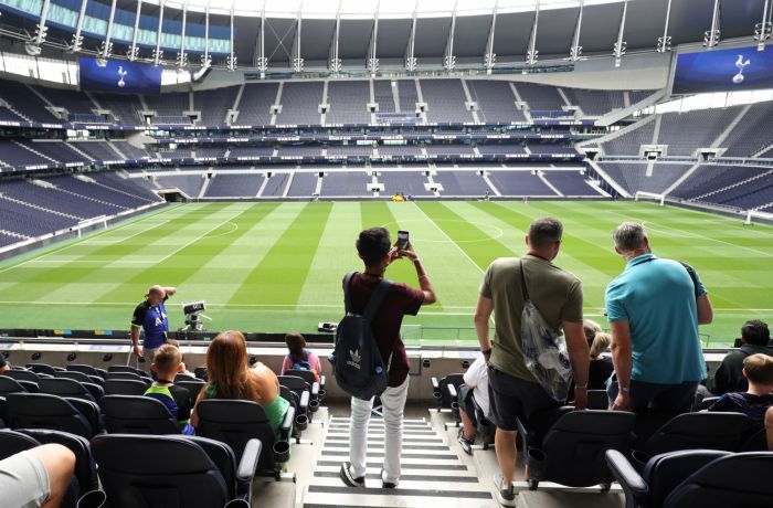 visitors in the stands overlooking the pitch on the tottenham hotspur stadium tour in london