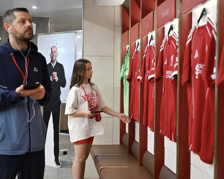 man and girl looking at shirts in dressing room of liverpool fc stadium tour