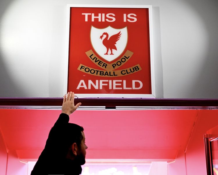 man reaching up to touch the this is anfield sign at liverpool fc