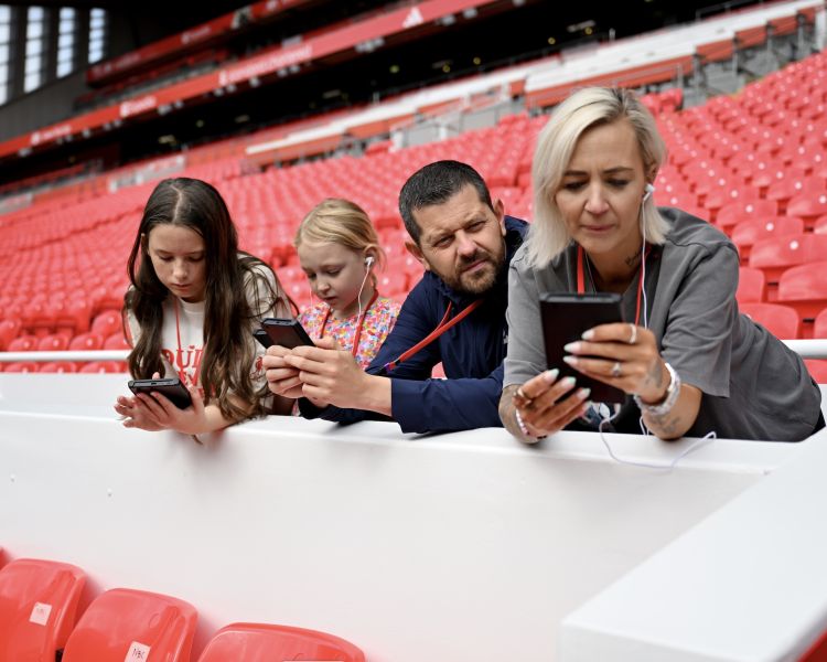 family looking at multimedia device on stadium tour at liverpool fc