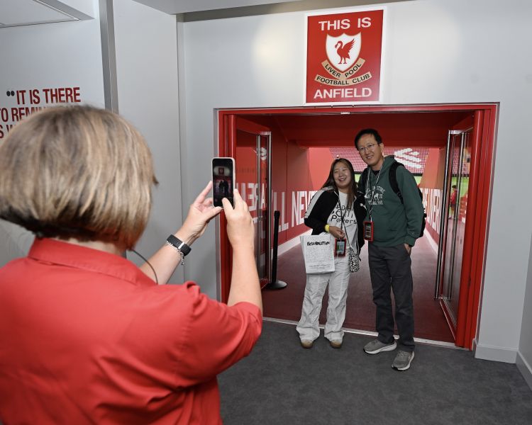 couple having their photo taken below the this is anfield sign at player tunnel