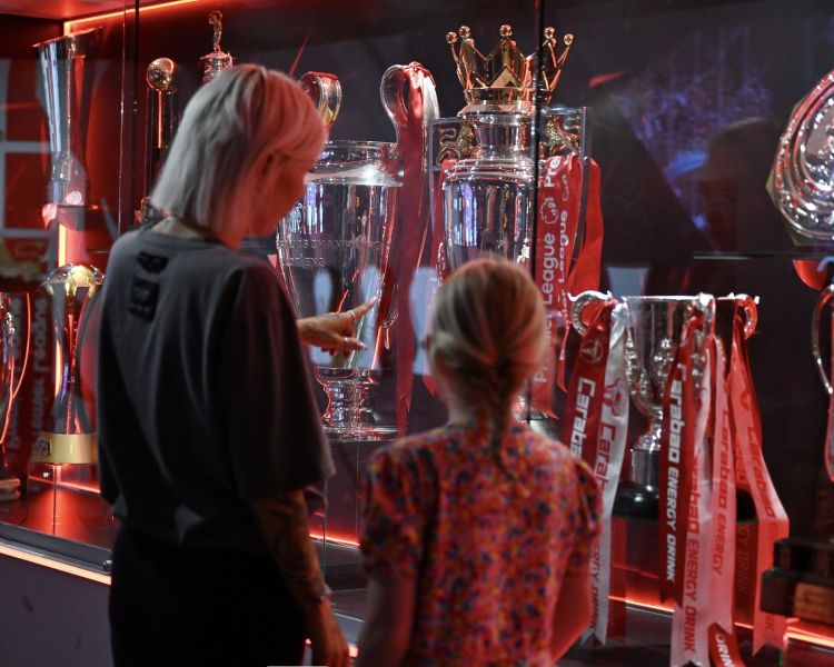woman and girl looking at display cabinet of trophies at liverpool fc museum