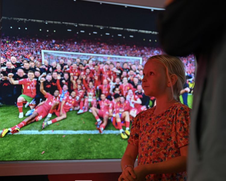 girl in front of large team photo at liverpool fc museum