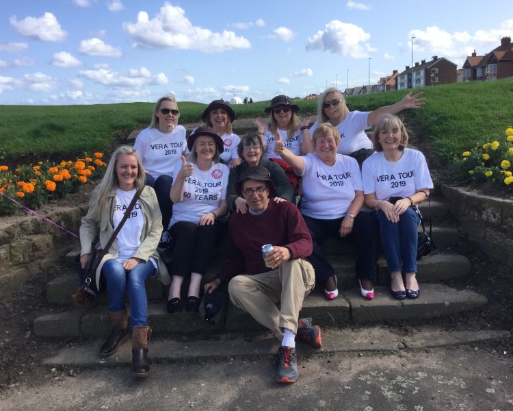 Group of ladies sitting on steps for photo on vera coach tour