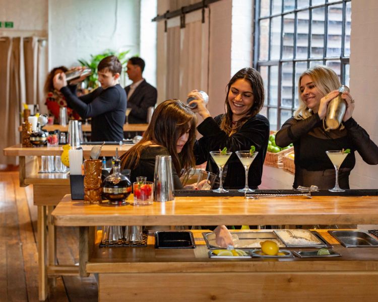 people at cocktail class making cocktails behind their bar stations