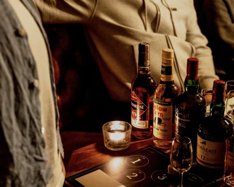 bottles of whisky on a table with candles for a whisky tasting experience in london