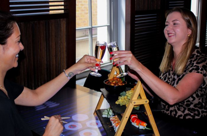 Two ladies saying cheers with fizz at asian afternoon tea