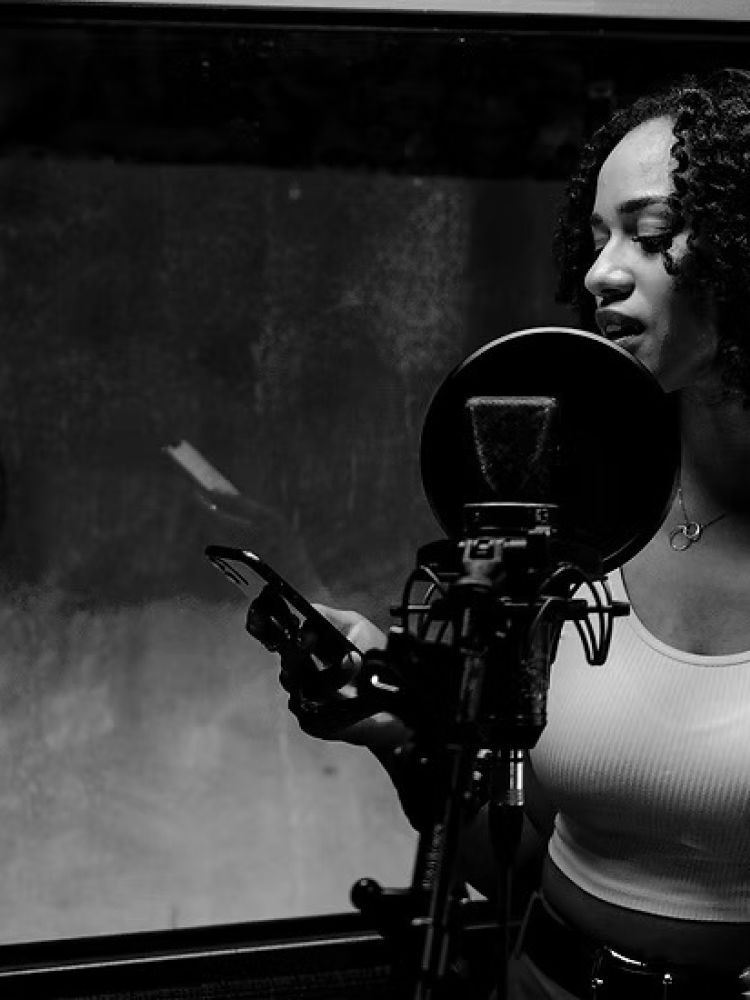 woman singing into microphone in recording studio